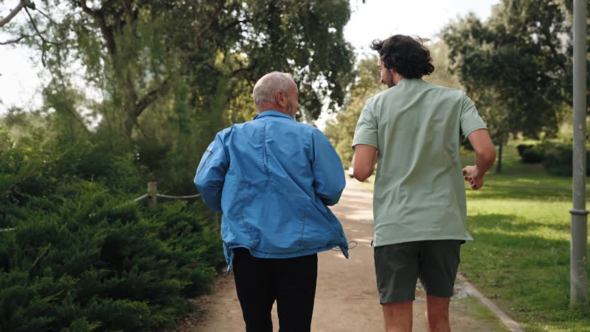 Backview of Senior man running doing sport together with his son, running for healthy retirement and family bonding
