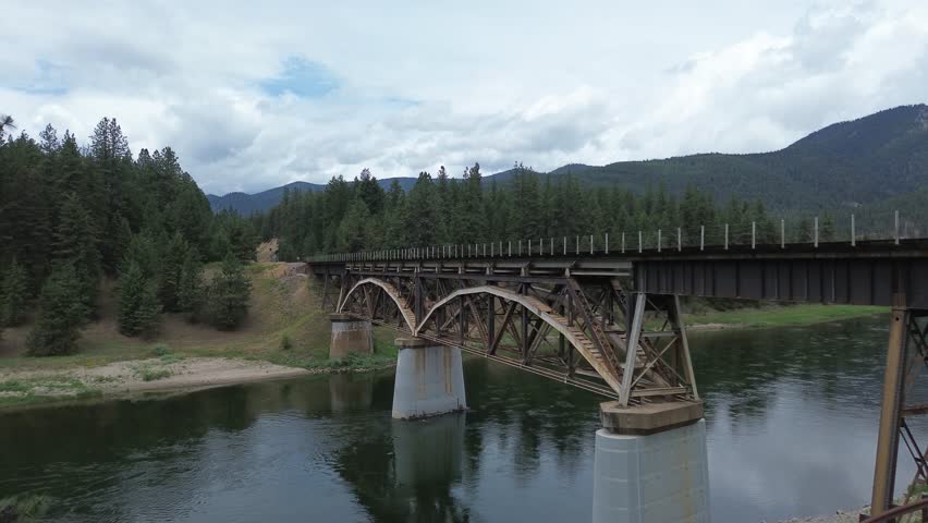 Railroad bridge over Clark Fork River in Montana. Unusual design is due to additional reinforcing structure to carry heavier trains. Rising shot that features the trusses of the bridge.