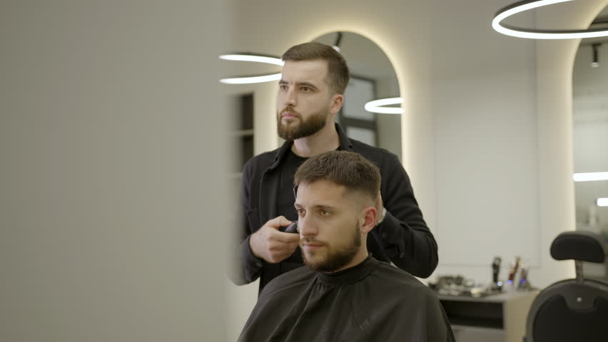 Professional barber giving haircut to client. Clip