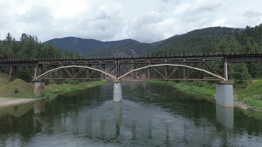 Railroad bridge over Clark Fork River in Montana. Unusual design is due to additional reinforcing structure to carry heavier trains. Close up side shot of the bridge that then rises over it.