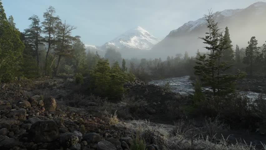 Hiker by a River Facing Majestic Snow Capped Lanin Volcano