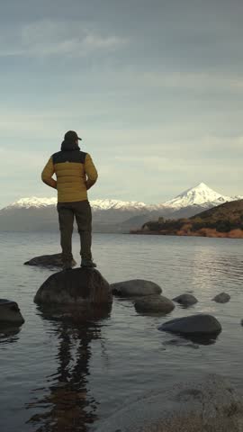 Man Standing on a Rock in Lake Huechulafquen Looking at Snow-Capped Lanin volcano