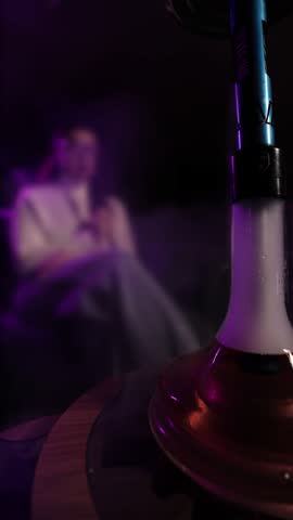 Girl smoking hookah in a café under neon light