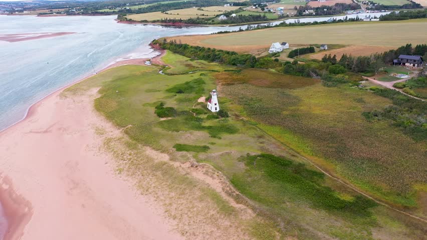 Aerial drone footage of the beautiful beach in Summerside, Prince Edward Island PEI in Canada showing the light house near the beach front and ocean on a sunny day in the autumn time