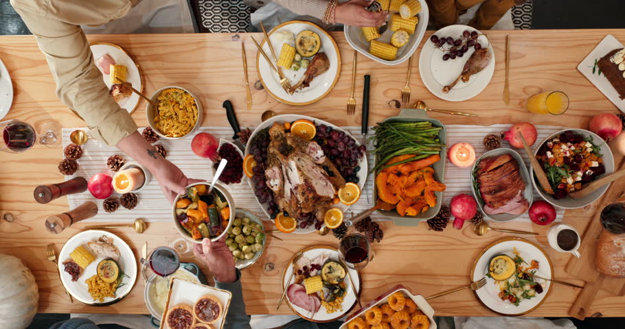 Above, hands and food with friends at dining room table together for thanksgiving celebration. Dish, meal and passing with group of people in home for event, sharing dinner or social gathering