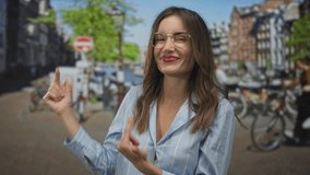 Smiling woman in blue shirt with glasses and broad grin finger pointing to sunlit canal on street; carefree joy. - Powered by Shutterstock - Get 15% off with code: PIKWIZARD15