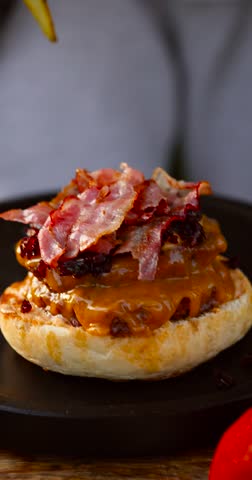 Vertical video of homemade grilled burger being assembled with sauce and fresh toppings on sunny day. Tasty juicy and appetizing 4k 60fps.