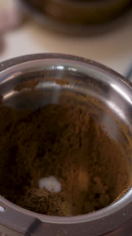Spoon lifts fresh ground coffee from grinder. Strong aroma spreads. Powder prepared for energizing coffee moment. Roasted coffee beans have been ground down to be brewed for coffee