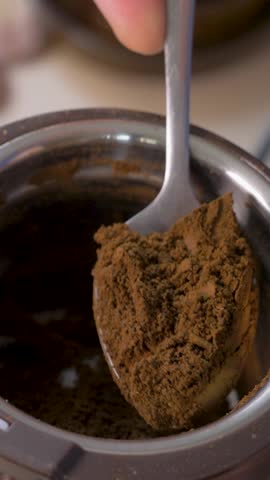 Spoon lifts fresh ground coffee from grinder. Strong aroma spreads. Powder prepared for energizing coffee moment. Roasted coffee beans have been ground down to be brewed for coffee