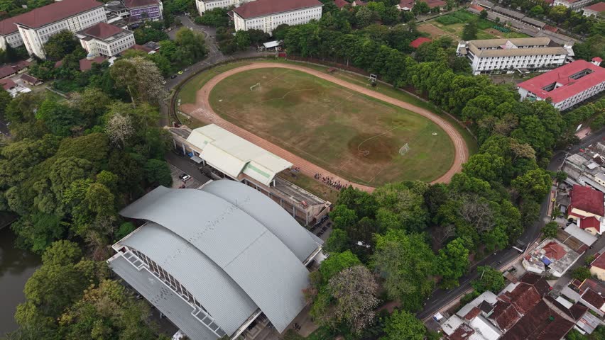 Aerial shot of Gadjah Mada University sports complex, visible athletic field and sports building. High quality 4k footage