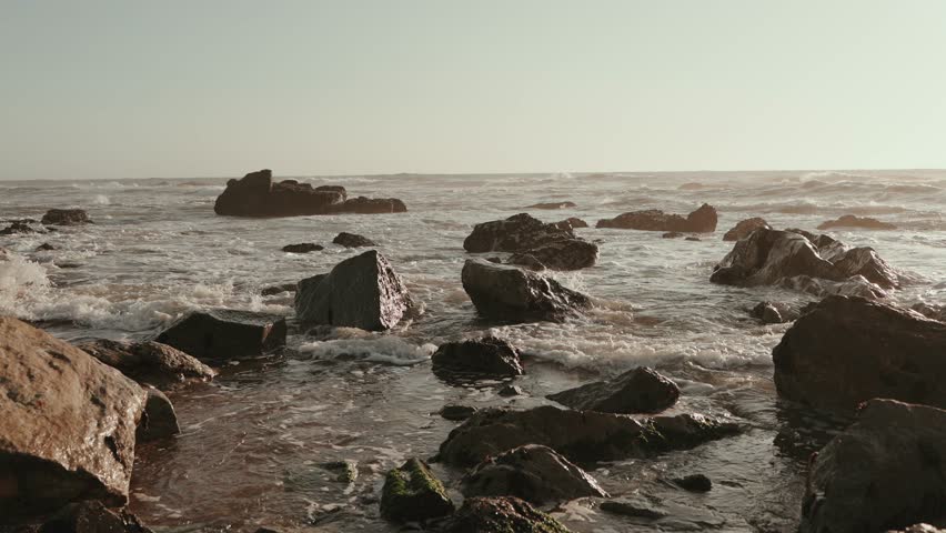 Peaceful ocean waves washing over rocks along the Atlantic coast at sunset in Portugal