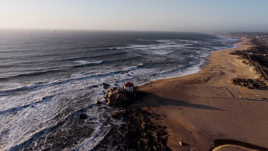 Capela do Senhor da Pedra chapel surrounded by Atlantic waves and golden sands at Miramar beach near Porto Portugal