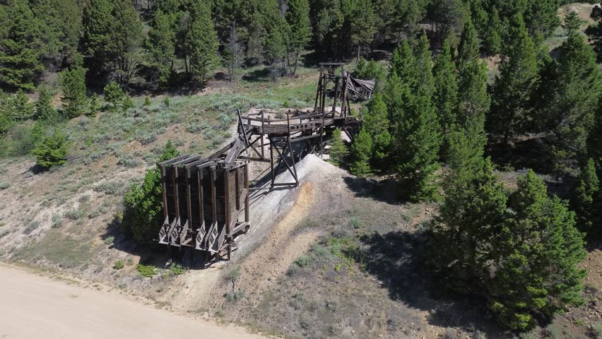 Ghost town of Comet Montana. Wide flyover shot of the ruins of the ore loading chute and tramway above it.