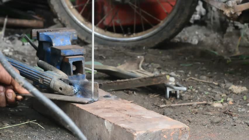 Skilled artisan forges heated metal on an anvil with hammer in during axe making setting.