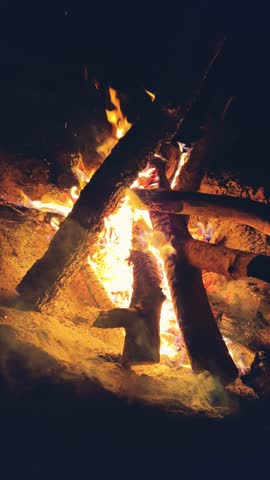 Astrakhan Region,Russia: A campfire on a sandy beach on the banks of the Volga River. A burning campfire on the banks of the Volga River in complete darkness. Sparks from the campfire, flames at night