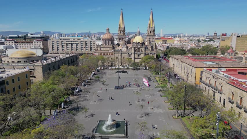 Aerial drone shot advancing at medium height through Plaza Tapatia showing people, trees and buildings