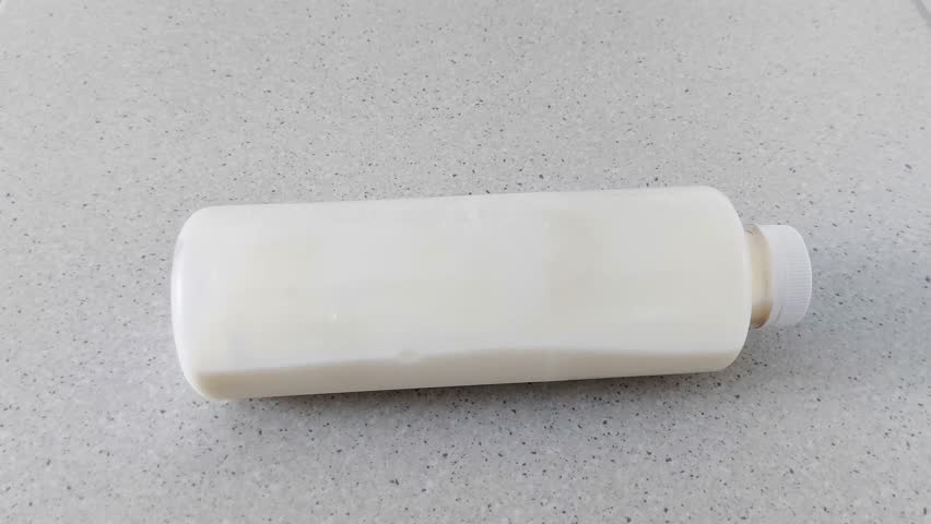White plastic bottle centered on a speckled countertop, surrounded by soft natural light. Minimalist setup with clean lines and neutral tones for a calm, modern aesthetic