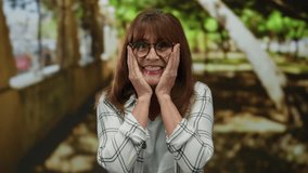 Hispanic senior woman smiling joyfully in an outdoor park, surrounded by nature, wearing glasses and a checkered shirt, expressing happiness and warmth amid leafy green trees and sunlight. - Powered by Shutterstock - Get 15% off with code: PIKWIZARD15