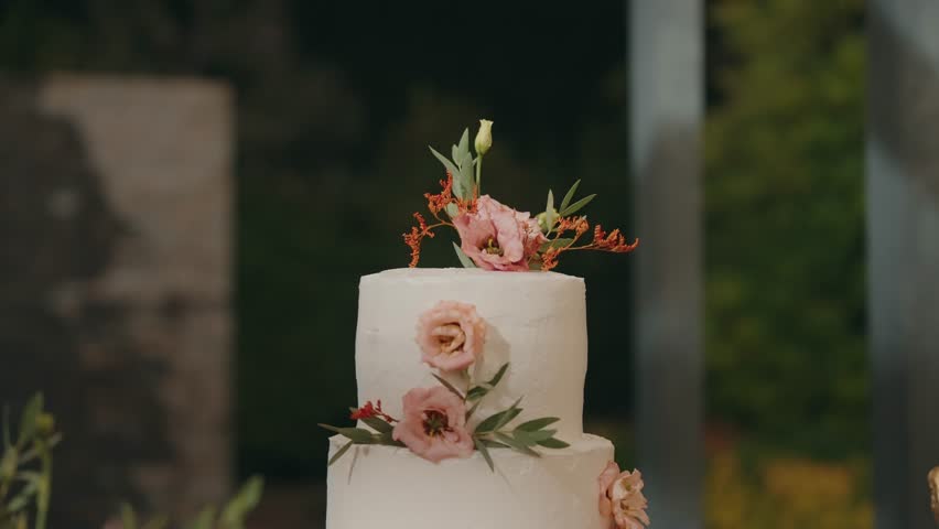 Two tier white wedding cake with floral decorations and natural leaves