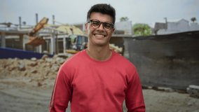 Young man smiling in red shirt on construction site in city showcasing friendly gesture in outdoor setting with urban background displaying attractive portrait. - Powered by Shutterstock - Get 15% off with code: PIKWIZARD15