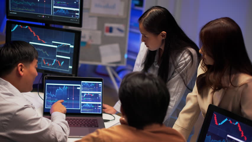 Asian business professionals working late night in modern office analyzing charts, discussing financial strategy, and reviewing market data across multiple monitors. Team collaboration and insight. - Powered by Shutterstock - Get 15% off with code: PIKWIZARD15