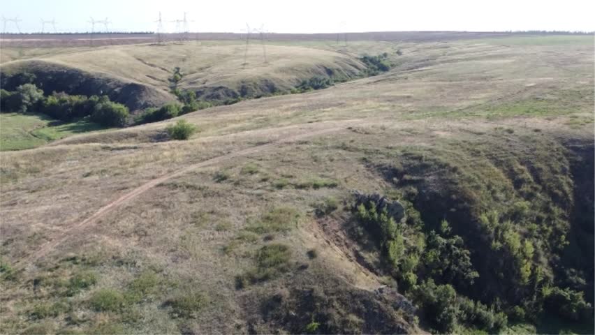 Summer view of a rocky gorge leading into a lush valley with a meandering creek in the wild, rural landscape of Eastern Ukraine