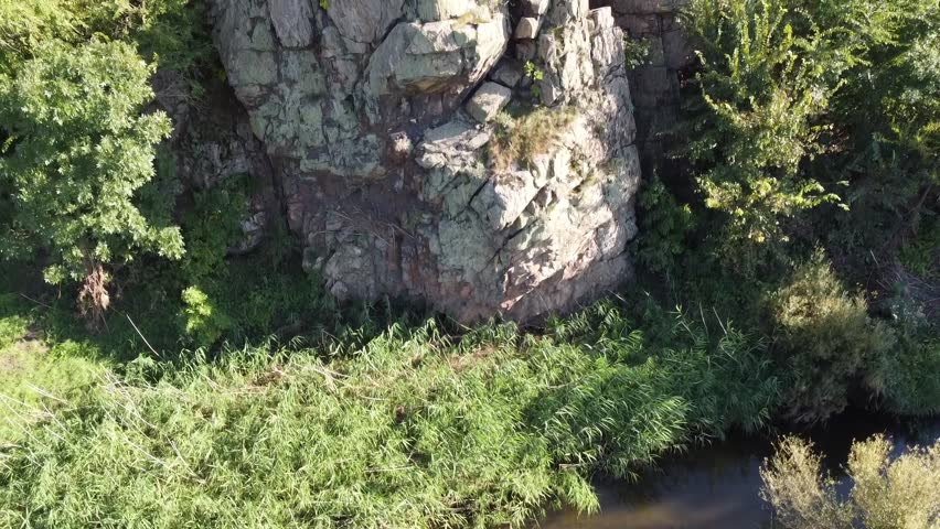 Summer view of a rocky gorge leading into a lush valley with a meandering creek in the wild, rural landscape of Eastern Ukraine