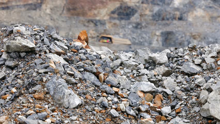 Mining work for gold ore. Yellow truck working on open pit mine.