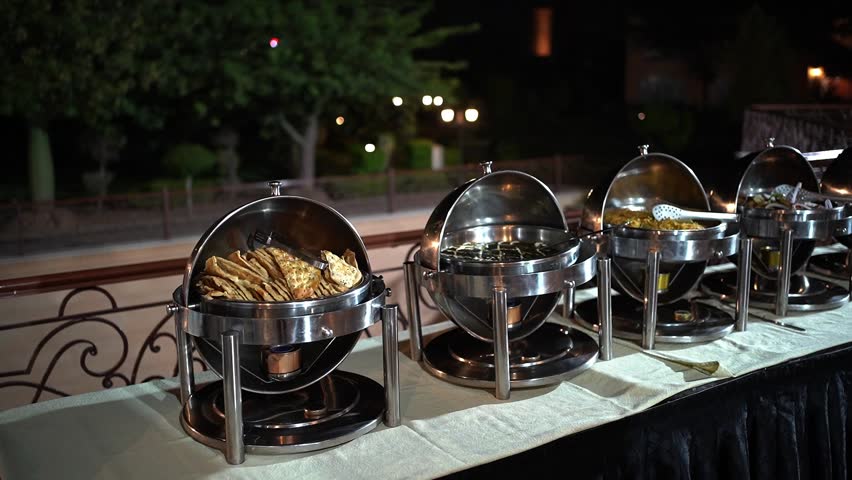 Luxury Buffet Table Setup with Food Warmers and Elegant Lighting at Event Dinner. Perfect for showcasing catering services, hotel banquets, wedding receptions, and fine dining events. 