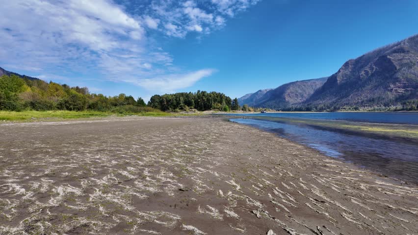 4K footage of Columbia River seen from Doetsch Day Use Area near Skamania, Washington, USA. Peaceful nature scene with blue water, mountains,  forested shoreline in early fall season under clear sky
