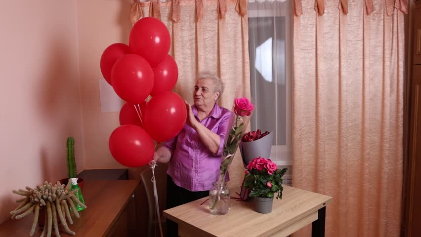 An elderly woman is preparing balloons to decorate a room.