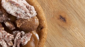 Top view of a delicious cookie topped with caramel, cream, and sugared pecan, displayed on a rotating wooden plate. - Powered by Shutterstock - Get 15% off with code: PIKWIZARD15