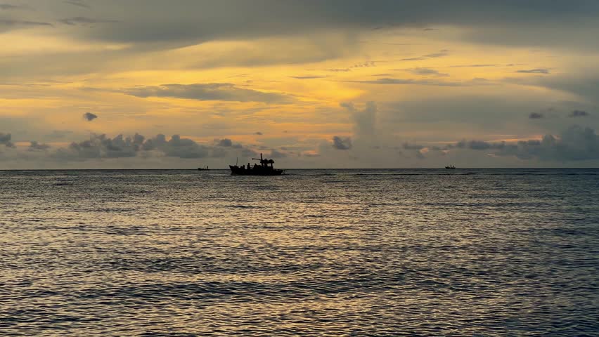 Fishing boats are sailing in the middle of the sea at sunset.