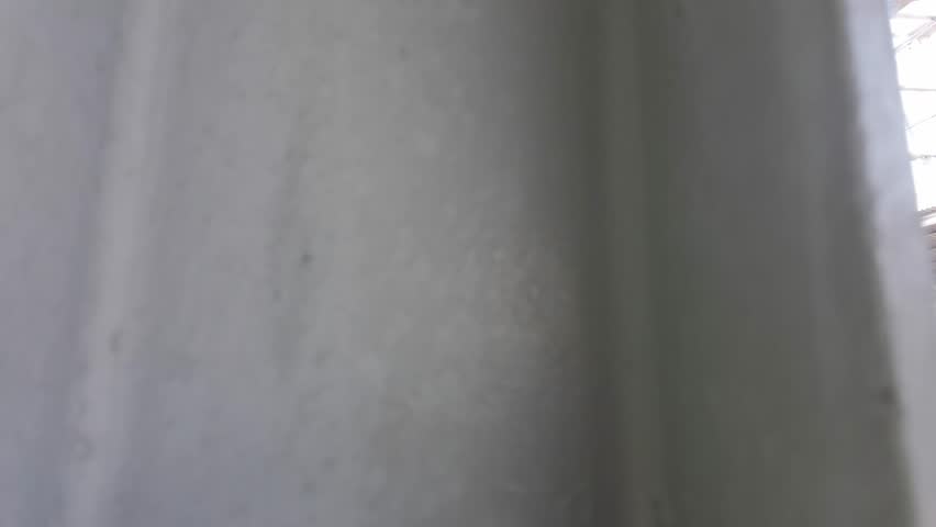 A view of a train station platform with tracks, shelter, and overhead wires. The platform is empty, and the sky is bright.