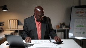 Elder african american businessman checking financial documents with a calculator while working late at his desk, showing a sequence of emotions from surprise to happiness and satisfaction - Powered by Shutterstock - Get 15% off with code: PIKWIZARD15