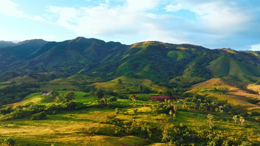 Summer mountain landscape under a cloudy sky. Grassy field and rolling hills. Rural landscape. Green mountains with grassy hills and blue sky on a summer day. Landscape video.