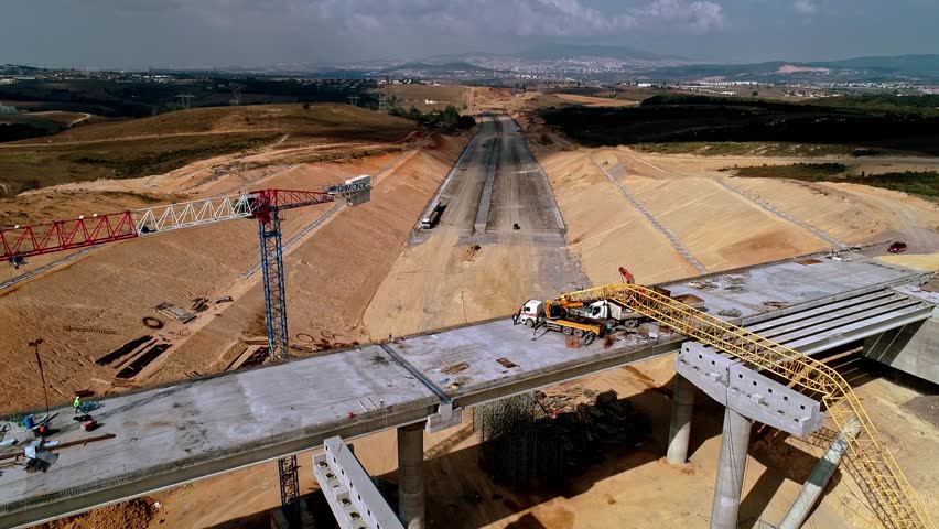 Drone footage of bridge and highway construction site with concrete work, steel structures, and heavy equipment. Large-scale infrastructure and civil engineering project.