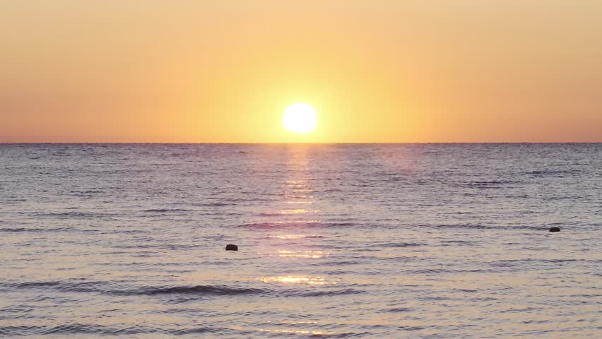 Sunrise bright sun shining above sea waves and clear blue sky, serene seascape view