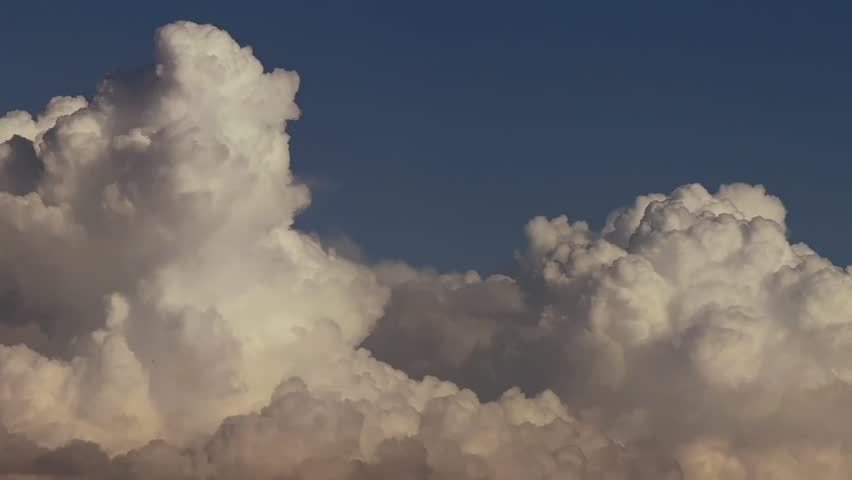 Evolving storm clouds bathed by the sunset light under a deep blue sky, An ever-changing cloudscape the reveals the motion of the sky.