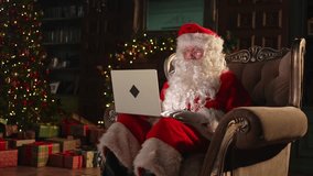Merry Christmas. Santa Claus with laptop reading letters from children typing buying presents gifts online. Santa with computer on Christmas eve. Mail gifts of Santa Claus. Winter Holiday Celebrations - Powered by Shutterstock - Get 15% off with code: PIKWIZARD15