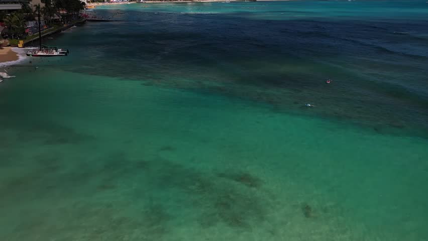 Aerial drone view showing Waikiki Beach skyline with Diamond Head crater, turquoise ocean water, and tall resort buildings under clear blue sky in Honolulu on Oahu Island, Hawaii