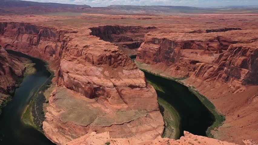 Aerial drone view showing Horseshoe Bend with Colorado River curving around massive red sandstone cliffs near Page Arizona revealing stunning desert canyon landscape and clear sky