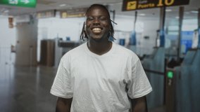Man young african american smiling with arms crossed at airport check in kiosks near gate turnstiles, wearing white t shirt and dreadlocks; confidence. - Powered by Shutterstock - Get 15% off with code: PIKWIZARD15