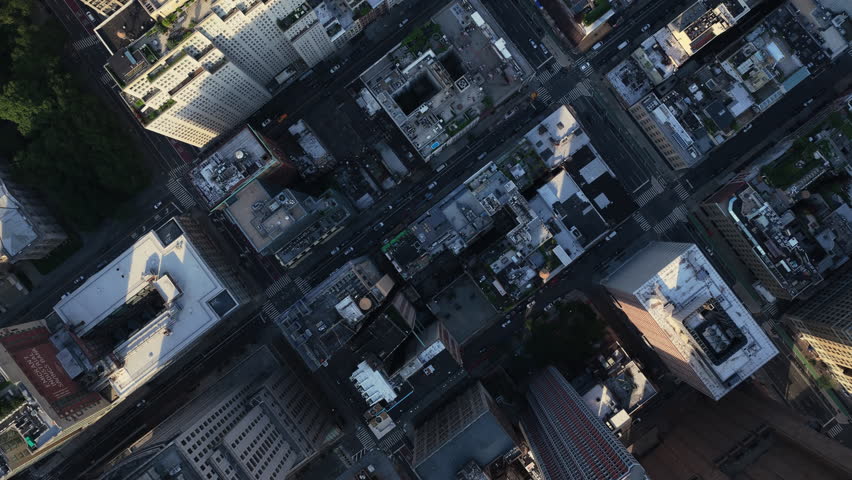 Overhead aerial shot of New York City's bustling Manhattan, highlighting iconic street blocks during a clear late afternoon
