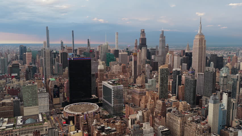 Aerial view of New York City's skyline during late afternoon, featuring iconic landmarks like the Empire State Building and Chrysler Building