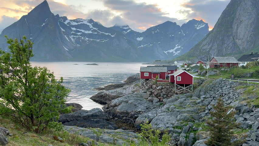 Picturesque norwegian fishing village of Reine with majestic snowy mountains in the background