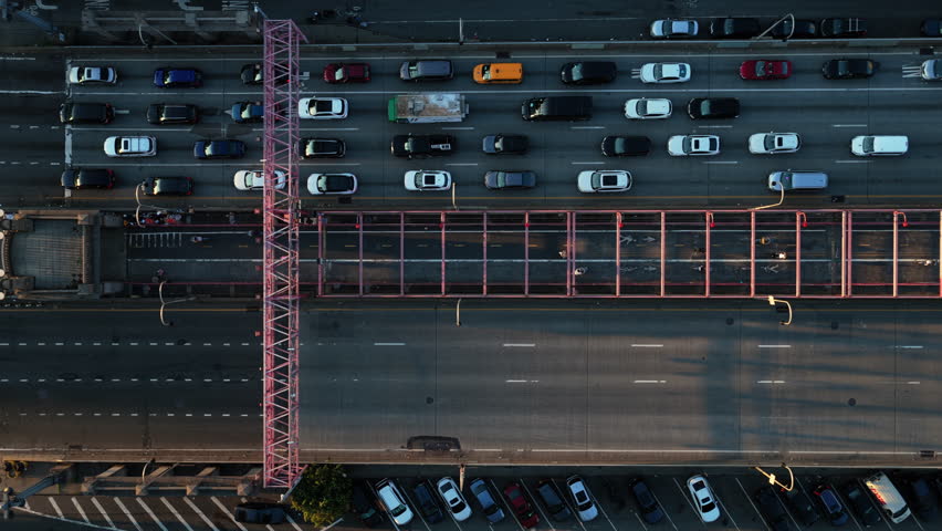 Overhead aerial view of the Williamsburg Bridge in New York City, capturing the bustling traffic and iconic shadow patterns during late afternoon
