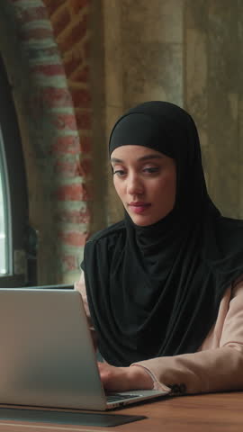 Muslim business team intern Arabian woman working laptop Indian man boss businessman coming helping advise businesswoman with computer work two office partners managers coworkers teamwork partnership
