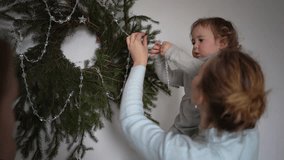 family with toddler and teenager decorates pine wreath, Christmas tree for home decor - Powered by Shutterstock - Get 15% off with code: PIKWIZARD15