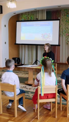 Kindergarten education. teacher conducts a group lesson with children in a spacious bright room. woman and children are dressed in national traditional clothes.